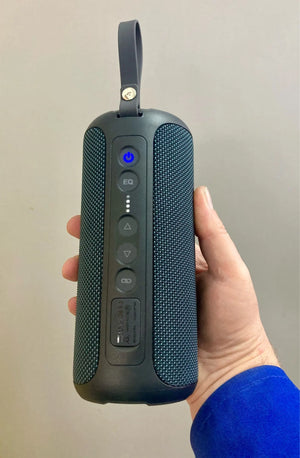 Black portable speaker held in a hand against a plain background