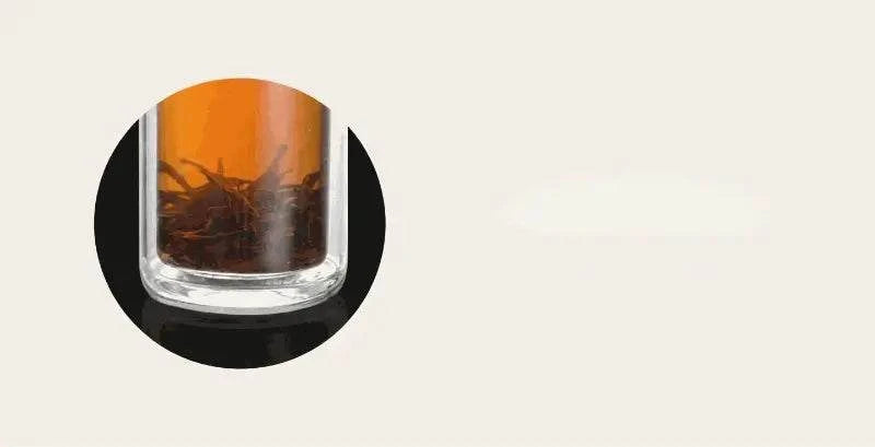 Glass with orange liquid and dark contents on a light gray background