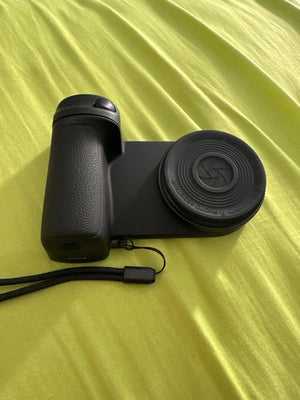 Black camera with lens cover on a yellow fabric background