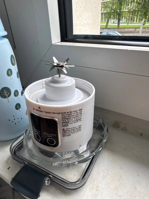 White kitchen appliance with clear base on a countertop near a window