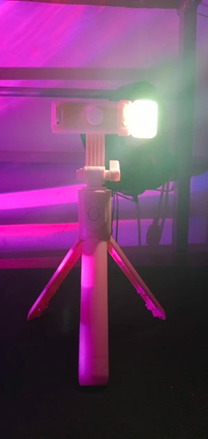 Light on a small tripod with a purple and pink gradient background