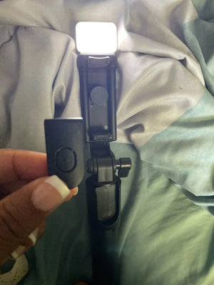 Hand holding a selfie stick with light on a textured surface