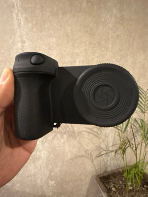 Black camera lens hood held by a hand against a neutral background