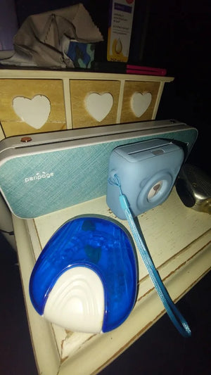 Small electronic device with a blue cover on a surface with heart designs.