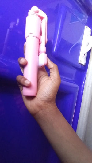 Hand holding a pink object against a blue background