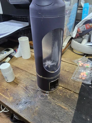 Black water bottle on a cluttered desk