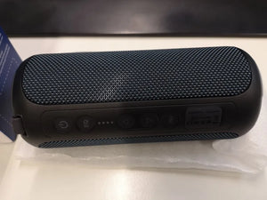 Black portable speaker on a white surface with a blurred background