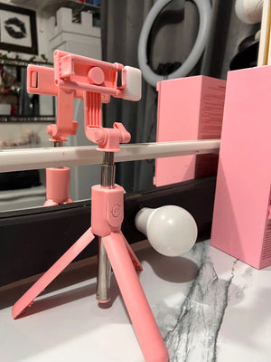 Pink phone holder with a tripod on a surface