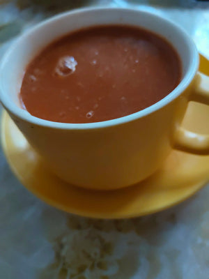 Yellow cup with red liquid on a matching saucer on a patterned surface