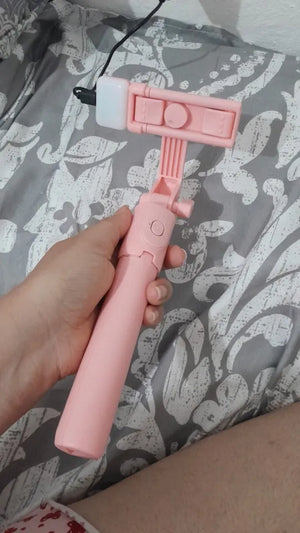 Pink handheld device with a camera and microphone on a patterned fabric background