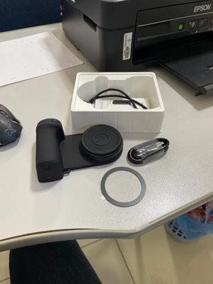 Camera lens and accessories on a desk with an Epson printer in the background
