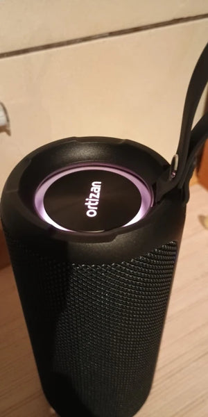 Black portable speaker with 'ortuzan' branding on a light wooden surface
