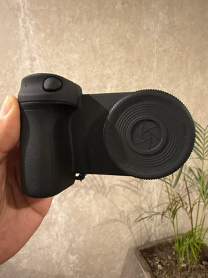 Black camera lens hood held by a hand against a neutral background