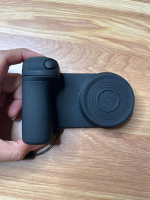 Black camera lens and grip on a wooden surface