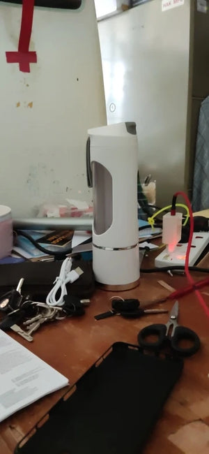 White cylindrical device on a cluttered desk with scissors and other items.