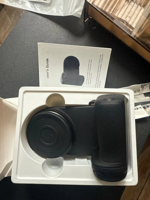 Black camera device in a white box with user guide on a dark surface