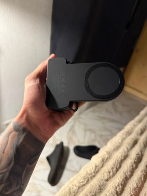 Person holding a black phone case with 'Caron' branding on a neutral background