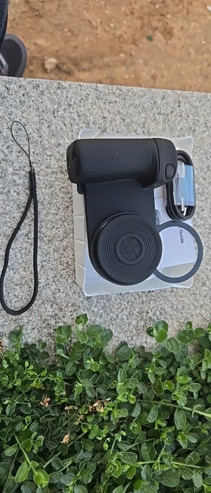 Black electronic device on a clear plastic stand with grass and concrete in the background