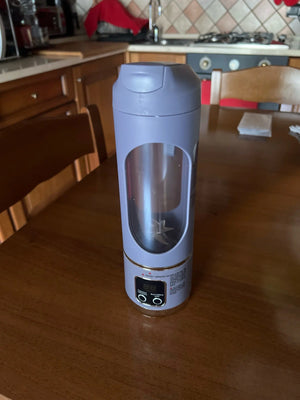 Purple travel mug with clear window on a wooden table in a kitchen.