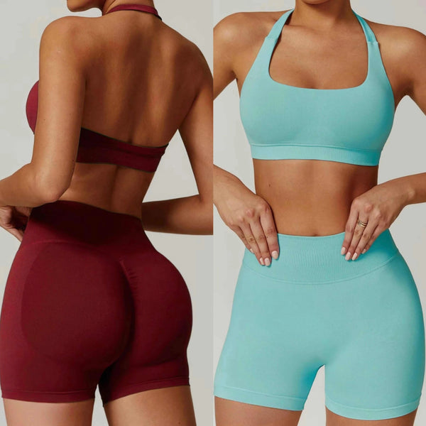 Two women wearing maroon and teal sports bras and shorts on a plain background